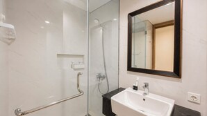 A modern bathroom with a glass-enclosed shower, a white sink, and a large mirror with a dark frame. - Serene 1Br With Nature View At Apartment Lavaya Nusa Dua Bali (Bali)