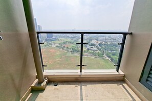 A balcony with a metal railing, a view of a cityscape, and a tiled floor. - Elegant Charming 1Br At Apartment Sky House Bsd (Tangerang)