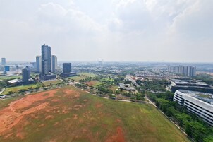 A cityscape with high-rise buildings, a large open field, and a modern bridge.