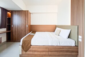 Ett modernt hotellrum med en säng i trä, en garderob och ett nattduksbord.