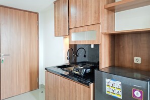 Eine kleine Küche mit Holzschränken, einer schwarzen Arbeitsplatte und einem eingebauten Gasherd.
