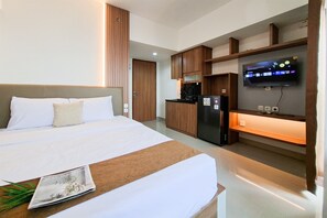 Ein Hotelzimmer mit einem Bett, einer Küchenzeile, einem Fernseher und einer Zeitschrift auf dem Tisch.