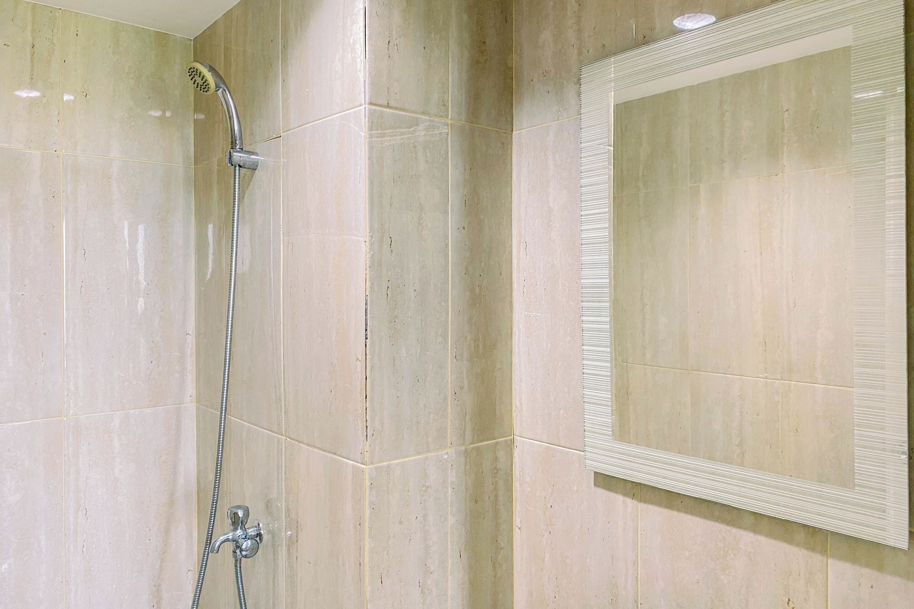 A bathroom with a shower, a mirror, and tiled walls.