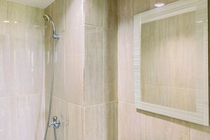 A bathroom with a shower, a mirror, and tiled walls. - Strategic And Cozy Studio At Apartment Podomoro Golf View (Depok)