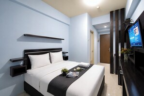A modern hotel room with a bed, bedside tables, a TV, and a small desk area. - Chic Minimalist Studio At Apartment Suites @Metro (Bandung)