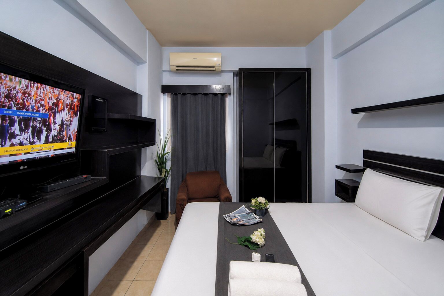Habitación de hotel con cama, televisión, escritorio, silla y armario.