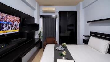 Habitación de hotel con cama, televisión, escritorio, silla y armario.