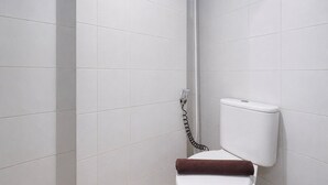 Ein Badezimmer mit weißen Fliesen, einer weißen Toilette und einer Duschkabine.