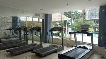 Une salle de sport équipée de tapis de course, d’un vélo d’appartement et d’un appareil d’aviron.