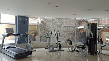 Un gimnasio con equipo de ejercicios, una cinta de correr y una pared con diseño de piedra.