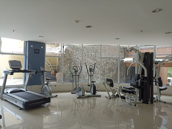 Un gimnasio con equipo de ejercicios, una cinta de correr y una pared con diseño de piedra.