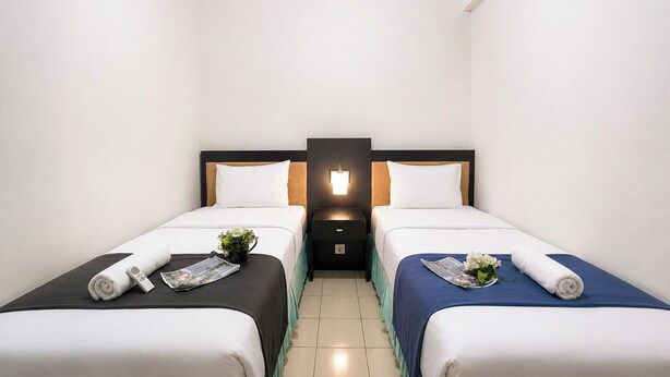 A hotel room with two beds, each with a pillow, a bedside table, and a small plant. - Homey 2Br (No Kitchen) At Apartment Marbella Suites Dago Pakar Bandung (Bandung)