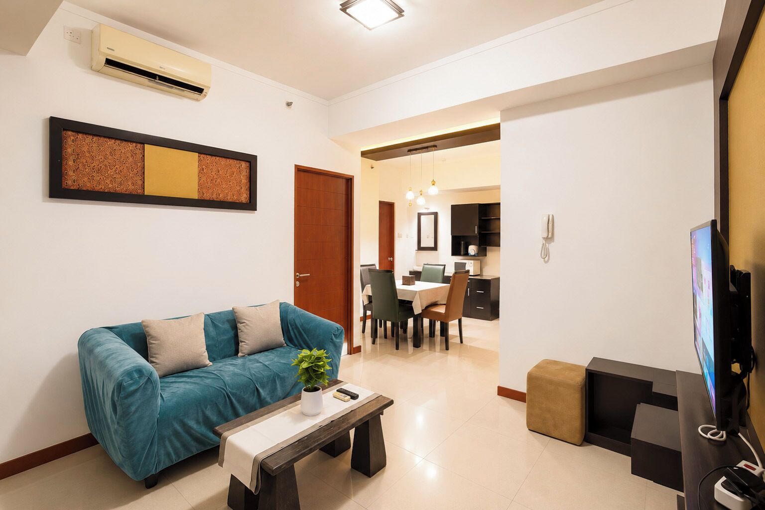 A living room with a sofa, a coffee table, a TV, and a dining area with chairs and a table.