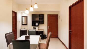 A dining area with a table, chairs, a microwave, and a sink.