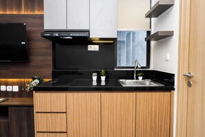 Eine moderne Küche mit schwarzer Arbeitsplatte, Holzschränken, einem eingebauten Backofen und einer Edelstahl-Spüle.
