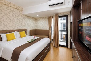 Ein Hotelzimmer mit einem großen Bett, einem Fernseher und einem Balkon mit Vorhängen.