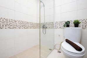 Un baño con ducha, inodoro y pared de azulejos con diseño de cuadros.