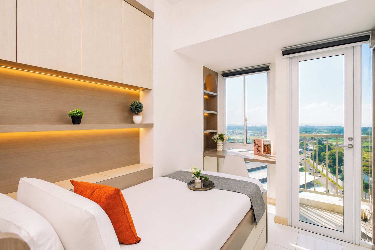 Une chambre moderne avec un lit, des tables de chevet et une vue sur la ville grâce à de grandes fenêtres.