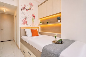 A modern bedroom with a bed, a nightstand, a wall-mounted shelf with plants, and a decorative wall mural.