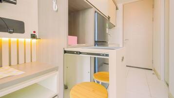 A compact hotel room with a kitchenette, a small dining table, and two stools.