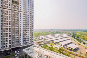 Un edificio de gran altura con varios balcones y un estacionamiento con espacios techados.