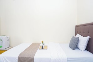 A neatly made bed with white bedding, a grey pillow, and a brown headboard. - Great Choice Studio Apartment At Margonda Residence 1 (Depok)