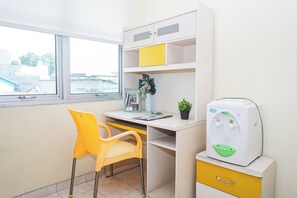 A room with a desk, a chair, a water dispenser, and a window. - Great Choice Studio Apartment At Margonda Residence 1 (Depok)