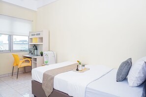 Hotellihuone, jossa on sänky, työpöytä, tuoli ja ikkuna.