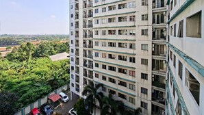 Un edificio residencial de varios pisos con balcones, zona de estacionamiento y vegetación circundante.
