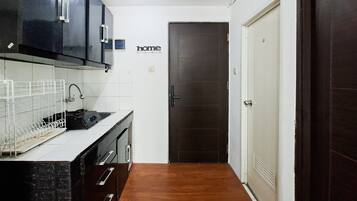 Una cocina con armarios oscuros, encimera blanca y suelo de madera.