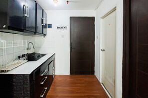 Una cocina con armarios oscuros, encimera blanca y suelo de madera.