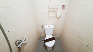 Un baño pequeño y estrecho con inodoro, ducha de mano y barra para toallas.