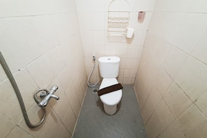 Ein kleines, schmales Badezimmer mit Toilette, Handbrause und Handtuchhalter.