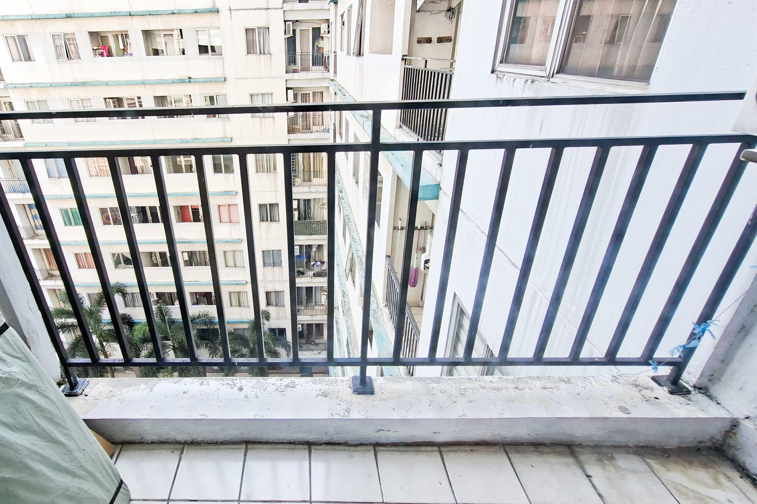 Un balcón con barandilla de metal que da a una zona residencial con varios edificios.