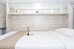 Ein modernes Schlafzimmer mit Etagenbett, Nachttisch mit Blumenvase und großem Spiegel über dem Bett.