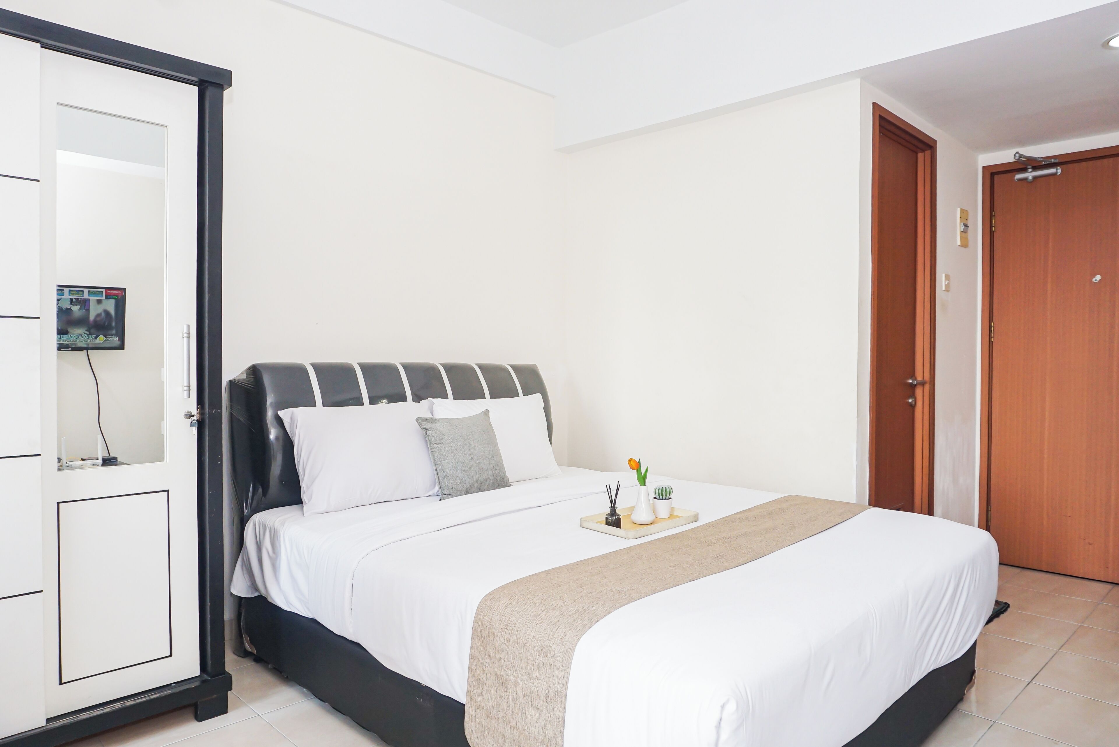 Ein Hotelzimmer mit einem Bett, einem Kleiderschrank, einer Tür und einem kleinen Tisch mit einer Vase und einer Pflanze.