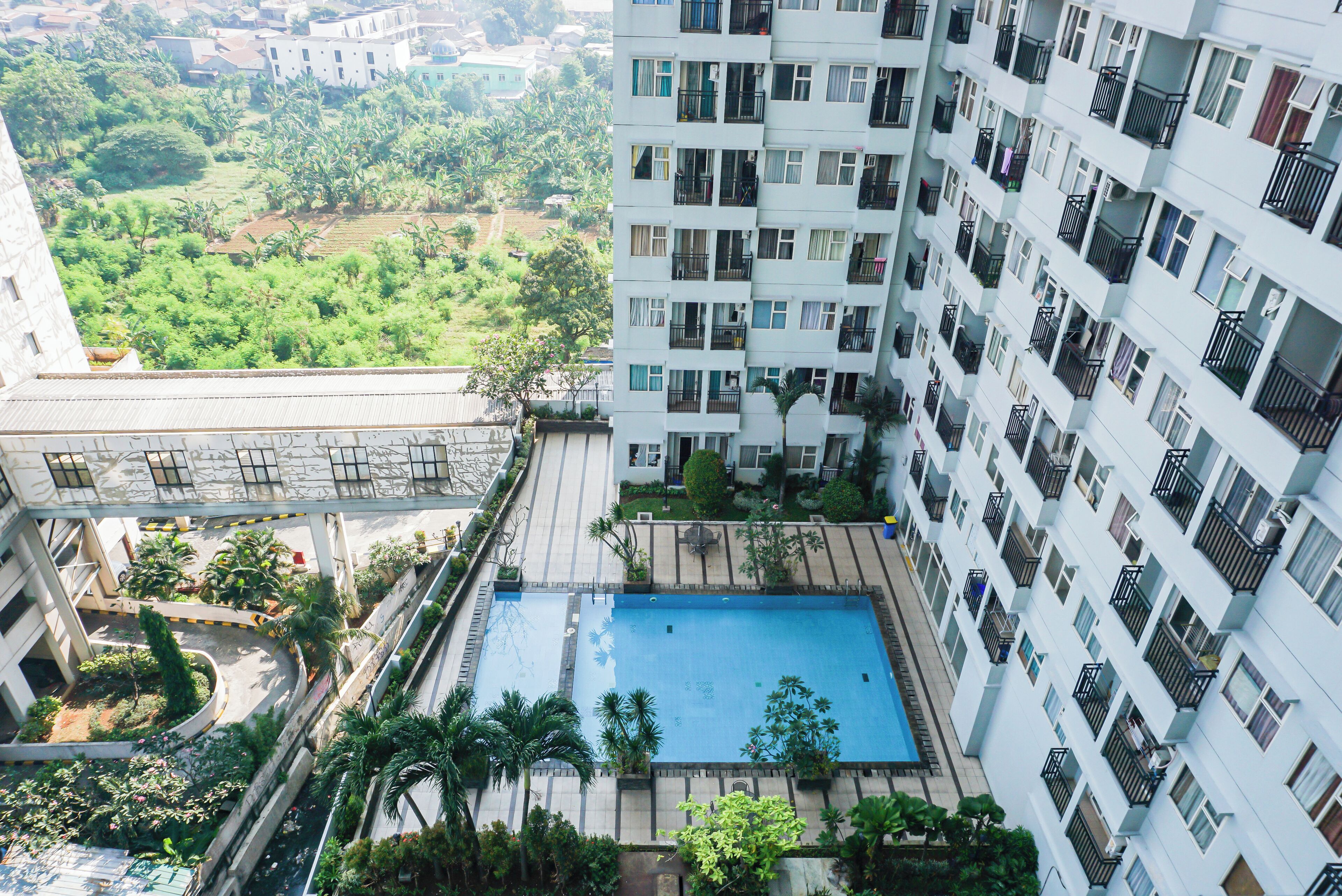 A high-rise building with multiple balconies and a swimming pool.
