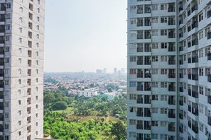 Un immeuble de grande hauteur doté de nombreux balcons et offrant une vue sur un paysage urbain composé d’immeubles résidentiels et d’espaces verts.