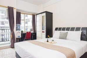 Une chambre d’hôtel équipée d’un lit, d’un bureau, d’une chaise, d’un distributeur d’eau et offrant une vue sur l’extérieur.