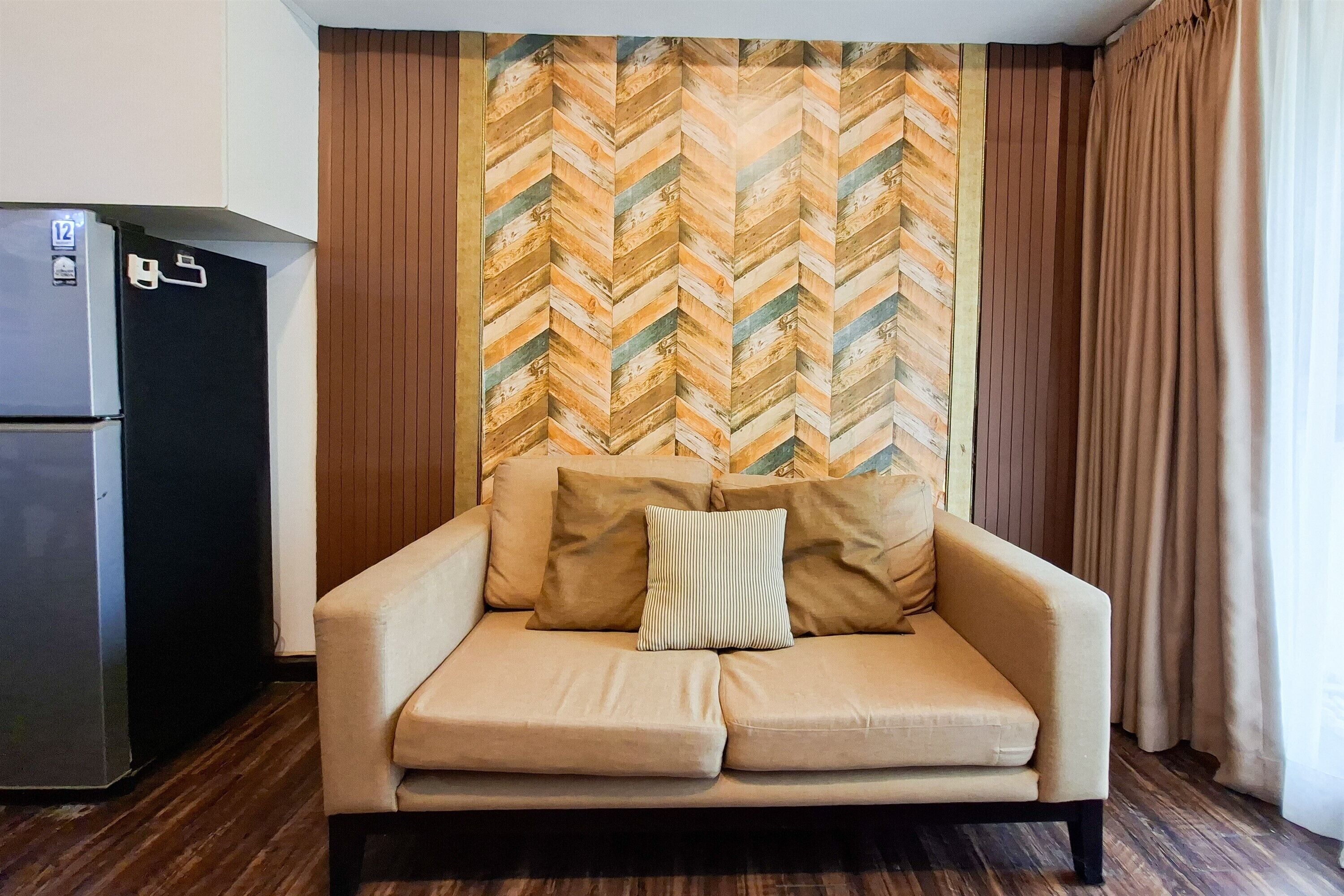 Une pièce comprenant un canapé, un réfrigérateur et un mur orné d’un motif en chevrons.
