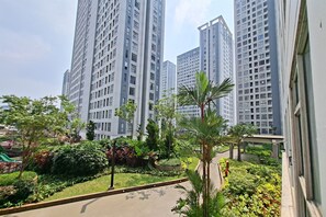 A residential area with high-rise apartment buildings, a paved walkway, and landscaped greenery. - Classic And Warm 2Br At Apartment M-Town Residence (Tangerang)