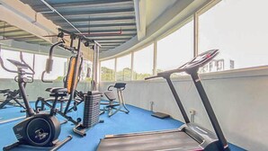 Ein Fitnessstudio mit Trainingsgeräten, darunter Laufbänder, ein Crosstrainer und Kraftgeräte.