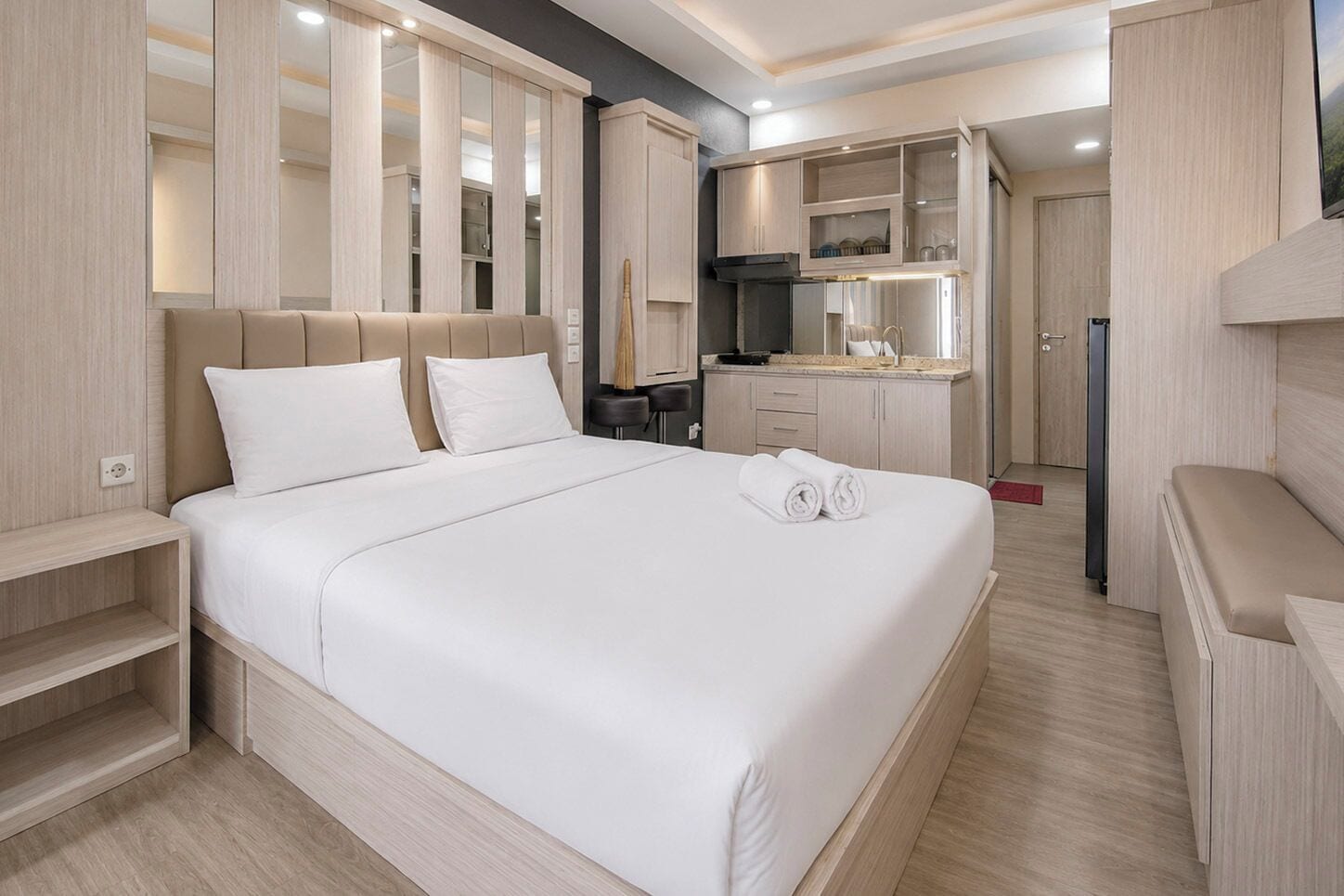Una habitación de hotel con una cama grande, un escritorio, una kitchenette y un baño.
