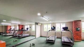 Un gimnasio con cintas de correr, un espejo y una alfombra verde.