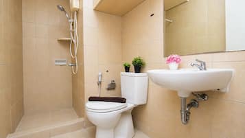 A bathroom with a toilet, a shower, and a sink.
