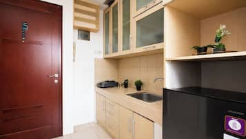 Una cocina compacta con puerta de madera, un refrigerador negro y un lavamanos.