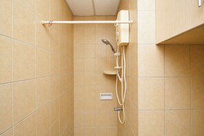 Ein Duschbereich mit Handbrause, Bedienfeld an der Wand und Handtuchhalter.