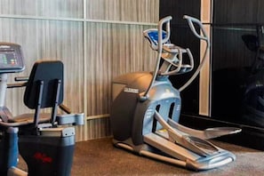 A gym with cardio machines, including a treadmill and an elliptical. - Decent Living In 1Br At Apartment Brooklyn Alam Sutera (Tangerang)