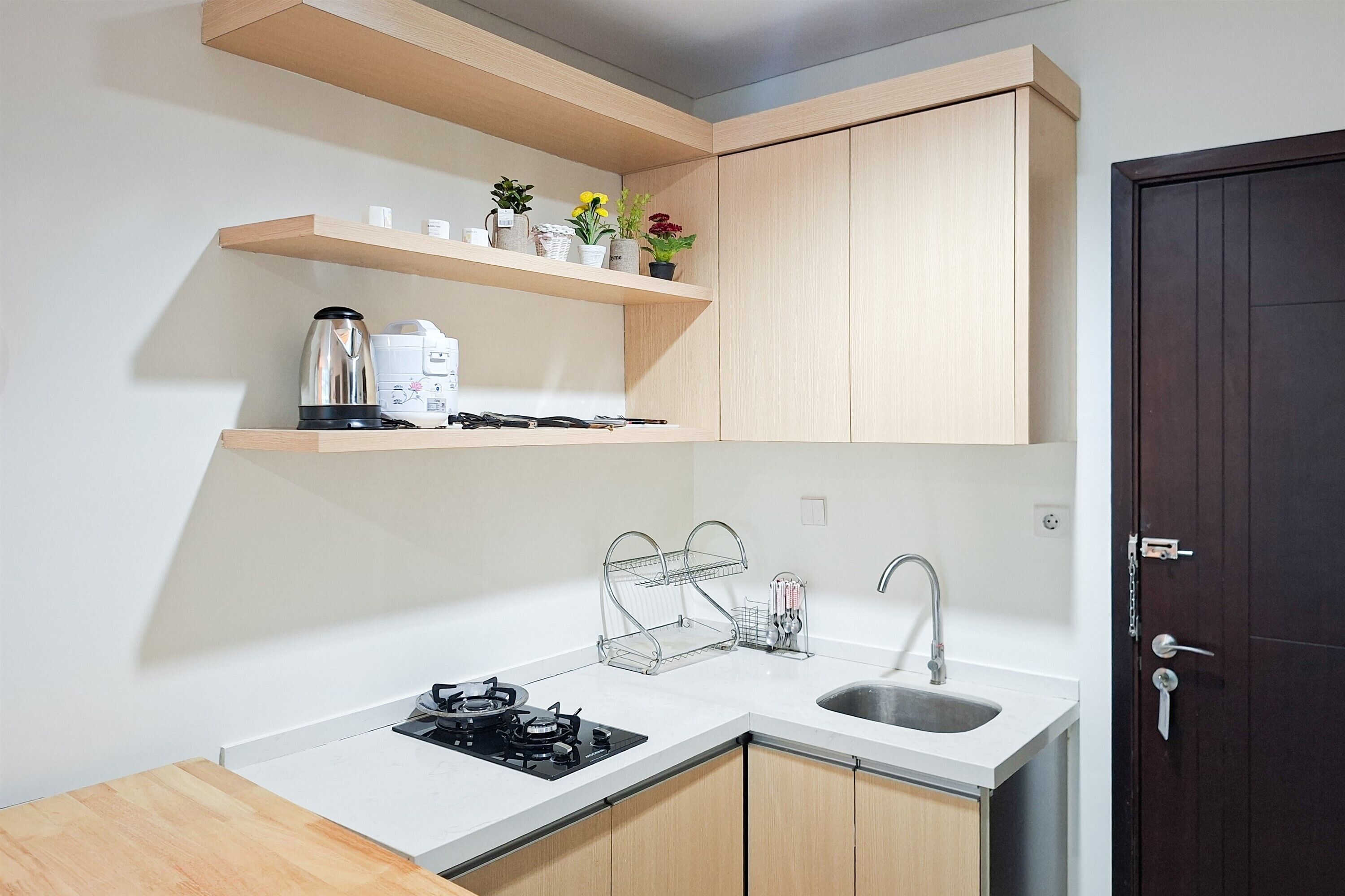 A compact kitchen with a white countertop, a built-in stove, a sink, and wooden cabinets.