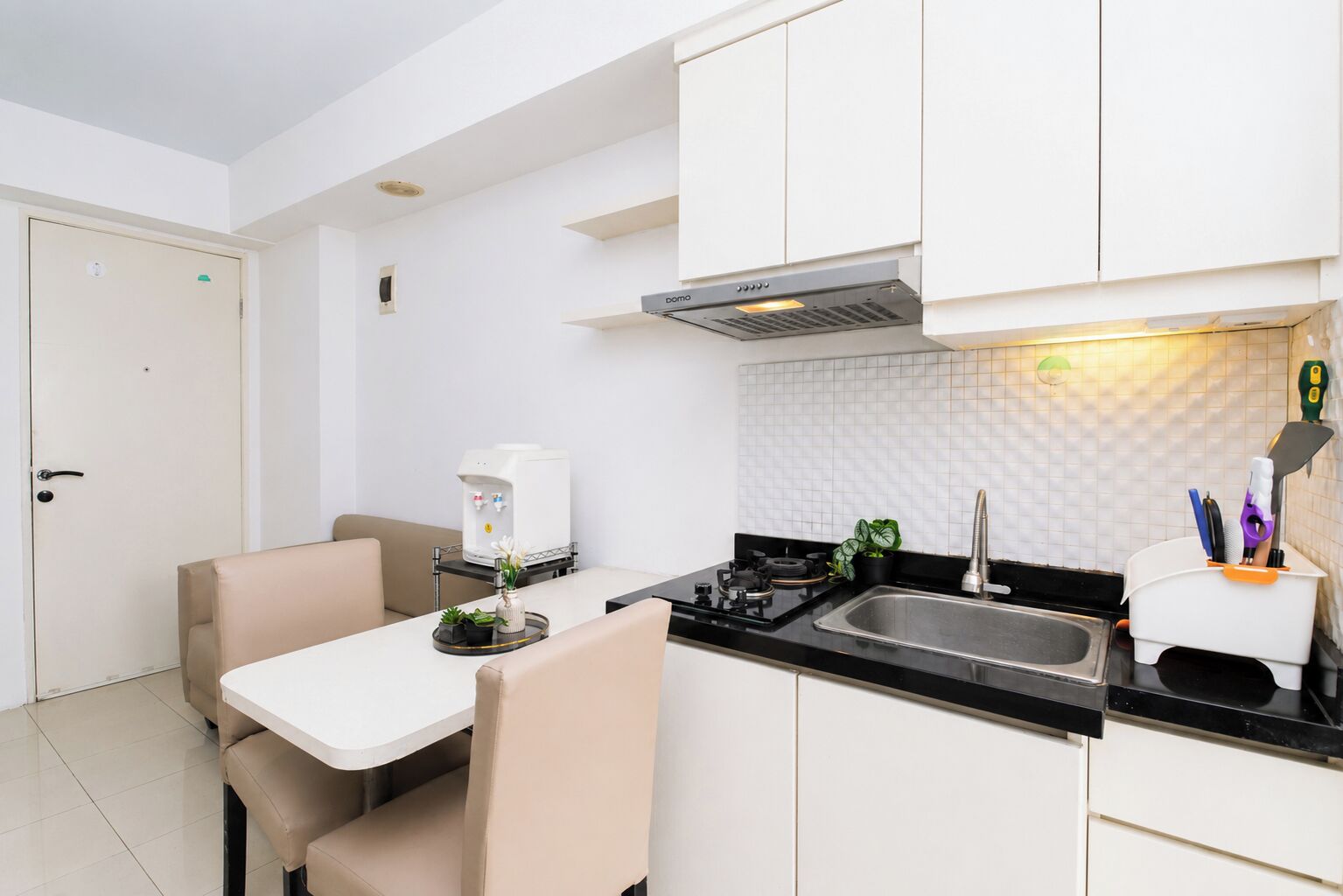 A compact kitchenette with a gas stove, sink, and a coffee machine.